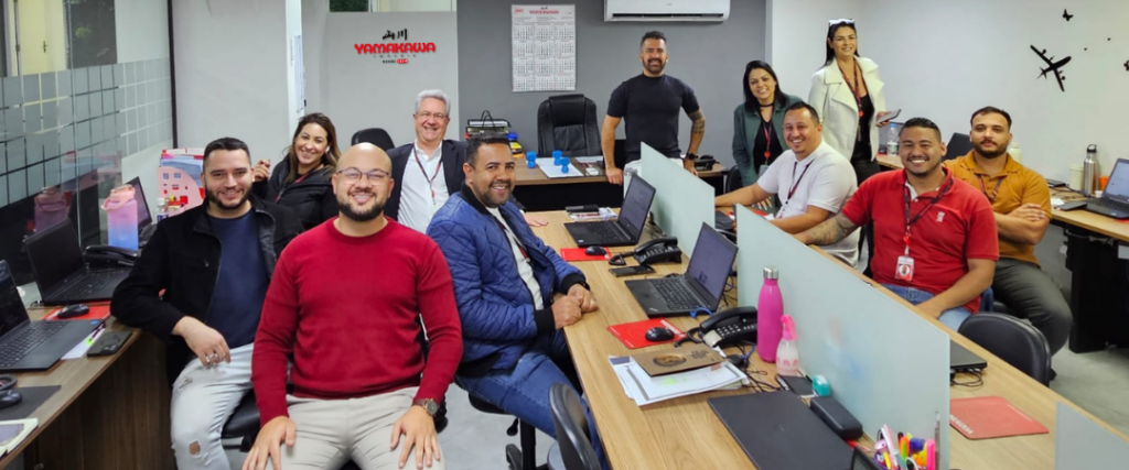 Parte da equipe da YAMAKAWA Imóveis reunida na unidade Tatuapé, sorrindo em ambiente moderno e acolhedor, representando a dedicação e o espírito colaborativo da empresa.